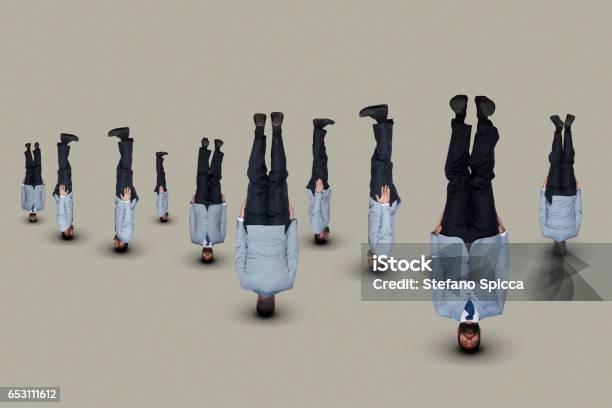 Upside Down Businessmen In Lightblue Suits Stock Photo - Download Image Now - Upside Down, Businessman, Headstand