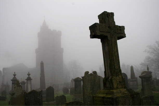 Spooky graveyard with cross in foreground and church outline in background
