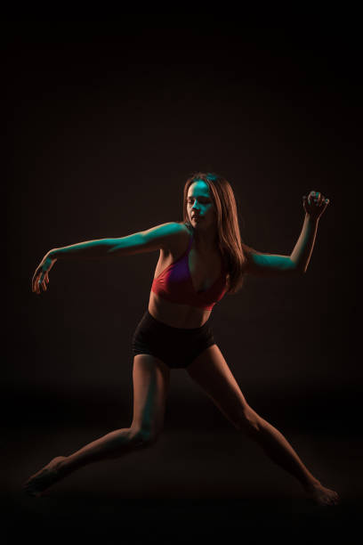 istock Young beautiful dancer in beige dress dancing on black background 653119636