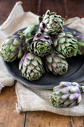 raw artichokes on a plate, ready to be cooked