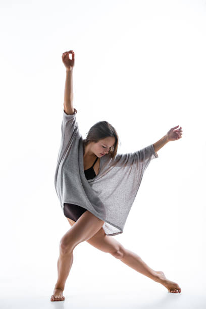 istock Young beautiful dancer in beige dress dancing on white background 653120602