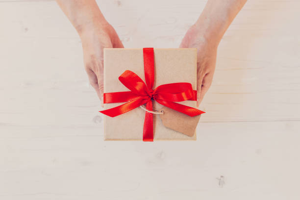 istock hand woman holding brown gift box on white wood 653120700