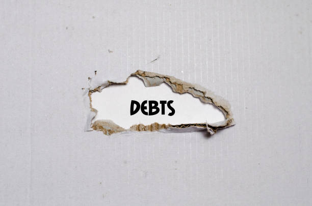 istock The word debts appearing behind torn paper 653123496