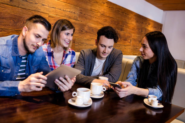 istock Friends using digital tablet and mobile phone at restaurant 653127496