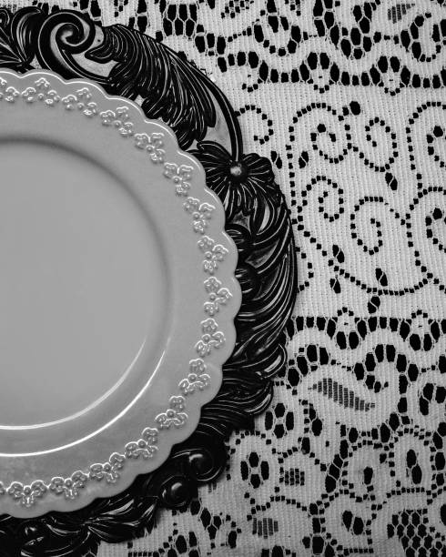 A lace tablecloth holds a delicate white plate on a carved wooden charger plate.