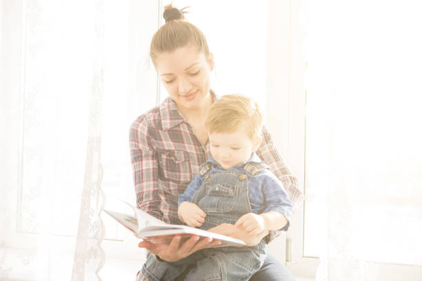 istock Mother reading with her son on a background of the window 653134882