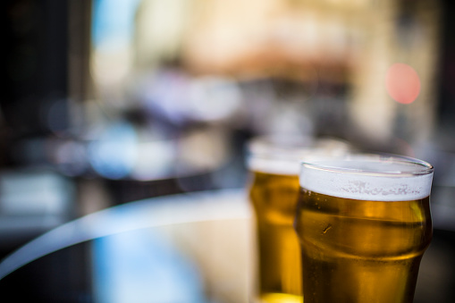 Close-up shot of two glasses of beer shot outside, in late afternoon light.