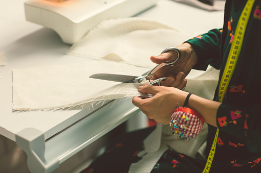 Female Tailor In Her Workshop. Cutting textile and making new clothes