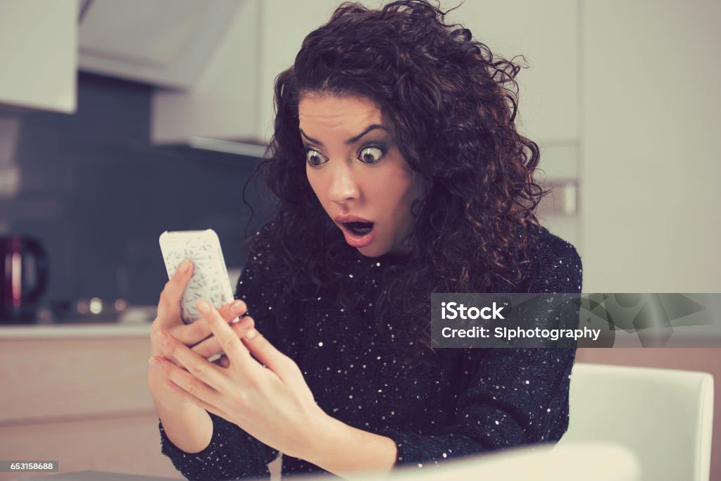 Closeup portrait funny shocked anxious woman Closeup portrait funny shocked anxious woman looking at phone seeing bad photos message with scared emotion on face Looking Stock Photo