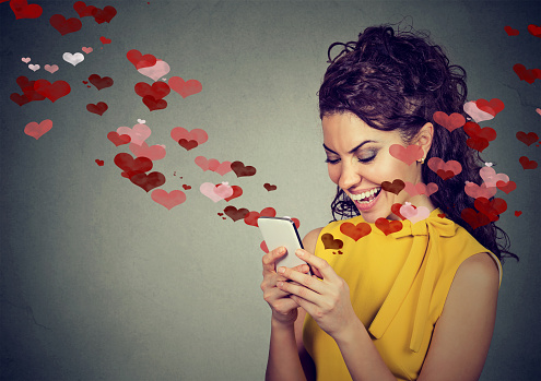 Hermosa mujer feliz enviando mensaje de texto de amor en el teléfono móvil con corazones rojos photo