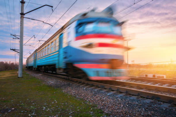 istock High speed passenger electric train in motion on railroad at sunset. Blurred old commuter train. Railway station against blue sky. Railroad travel, railway tourism. Rural industrial landscape. Concept 653171094
