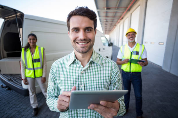 istock Portrait of manager using digital tablet and workers standing in background 653177802