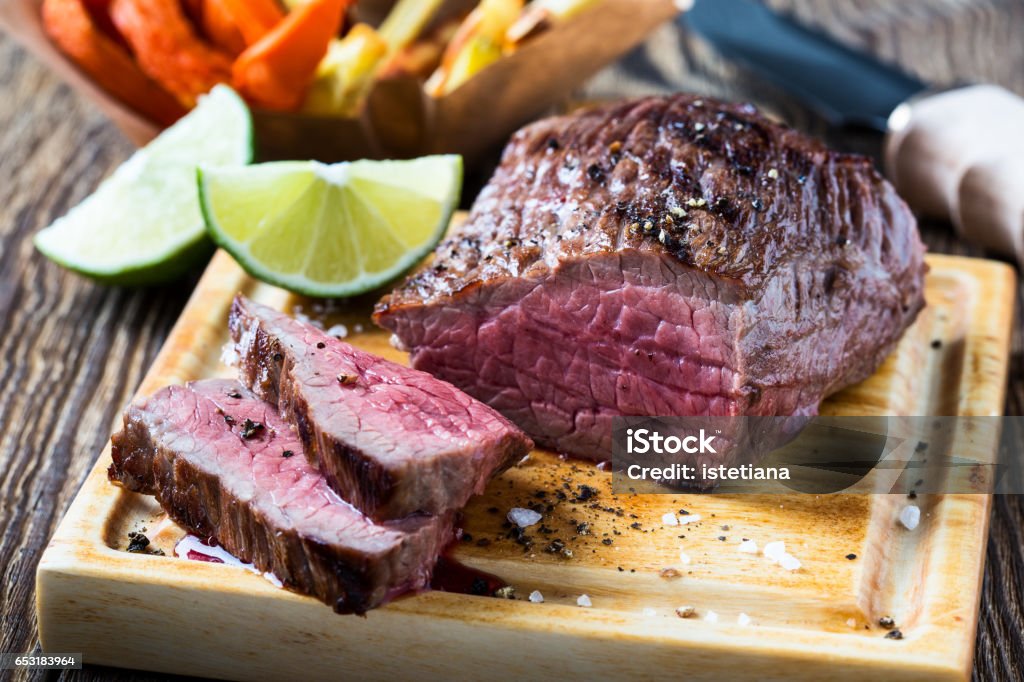 Rare roast beef sirloin Rare roast beef sirloin with french fries and slices baked pumpkin chips on cutting board Blade Stock Photo