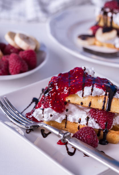 Belgian waffles with raspberries and double cream on white plate.