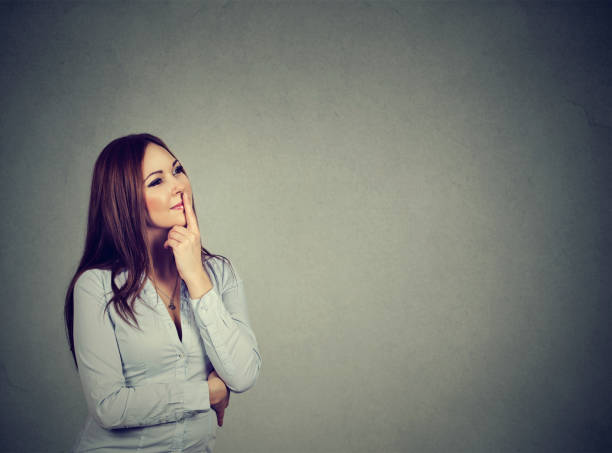istock happy woman thinking with hand on chin looking up 653194310