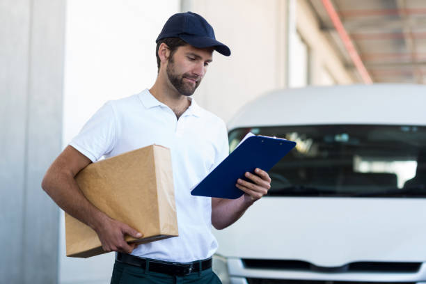 istock Delivery man holding a parcel and looking at clipboard 653194976