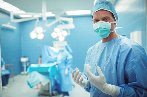 Portrait of male surgeon wearing surgical mask in operation theater at hospital