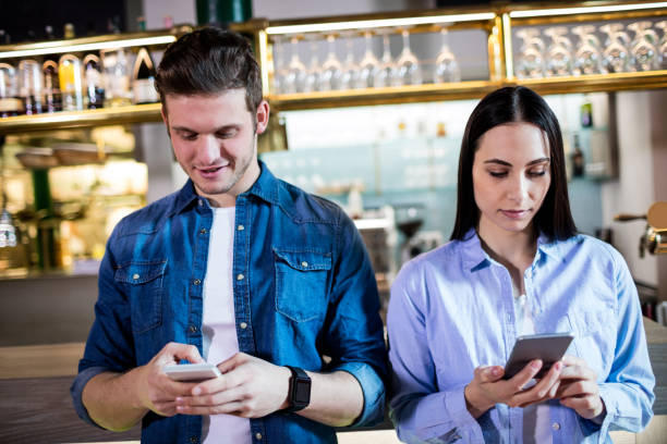 istock Man and woman using cellphone in bar 653201322