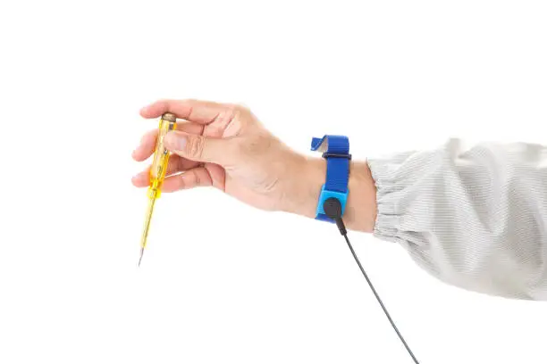 Photo of Bracelet on the hand of a man wearing ESD cloth holding a screwdriver, static resistance (ESD) bracelet or ground equipment, anti-static, used to safely ground is working. electronic devices