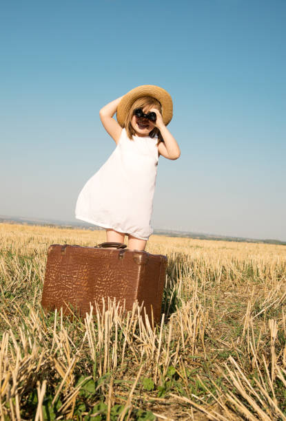 istock Little girl with suitcase is looking trough binoculars 653217522
