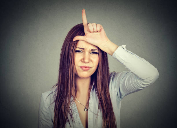 istock young woman giving loser sign on forehead 653217686