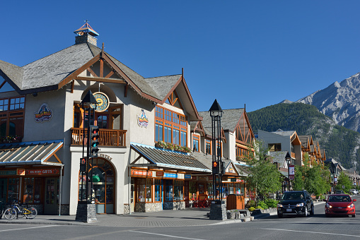 Banff, Canada - June 27, 2015. People driving on Banff Avenue in downtown, Banff, Alberta, Canada. Banff is a popular resort town about one and half hour's drive from Calgary and located right in the heart of Banff National Park. It is a starting point to explore the natural beauties of Canadian Rockies.