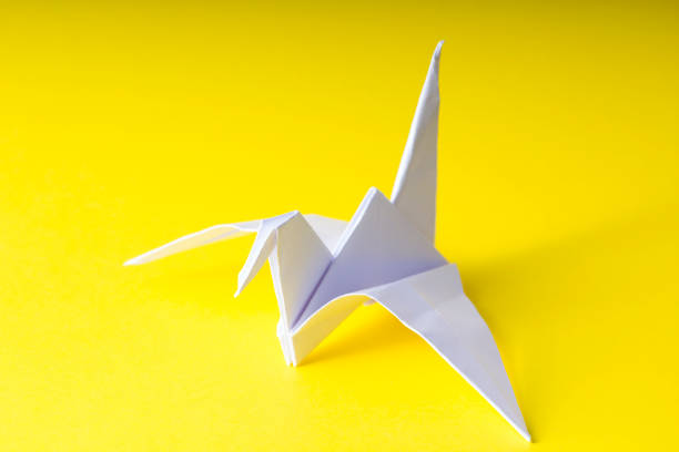 istock origami paper crane on yellow background 653225022