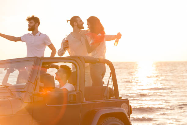 istock Five young people having fun in convertible car at the beach at sunset. 653234516