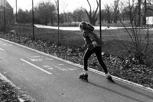 Young woman inline skating in a park. About 25 years old, Caucasian brunette.