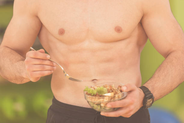 geprägt und gesunden bodybuilding mann hält eine frische salatschüssel geprägt bauch - eating body building muscular build vegetable stock-fotos und bilder