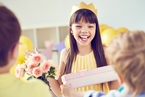 Cheerful Asian birthday girl enjoying her party and receiving gifts