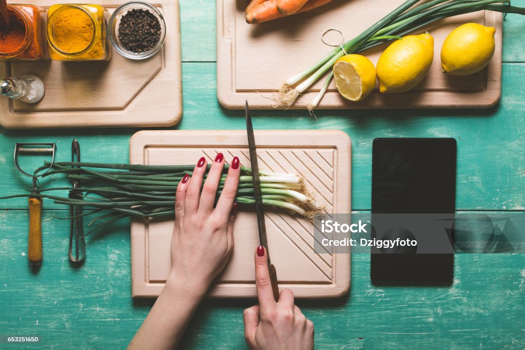 Cutting fresh vegetables Female person cutting fresh spring onion on a blue wooden table. View from above. Kitchen Counter Stock Photo