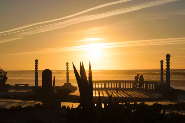 Beautiful image of the beach at Aglou Plage in Morocco hit by the last sunlight of the day, while two people looking at the horizon.