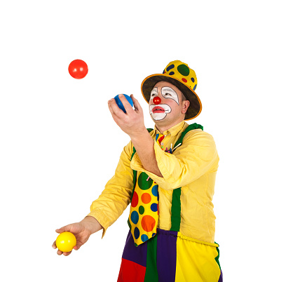 Funny clown in colorful costume juggling with balls isolated on white