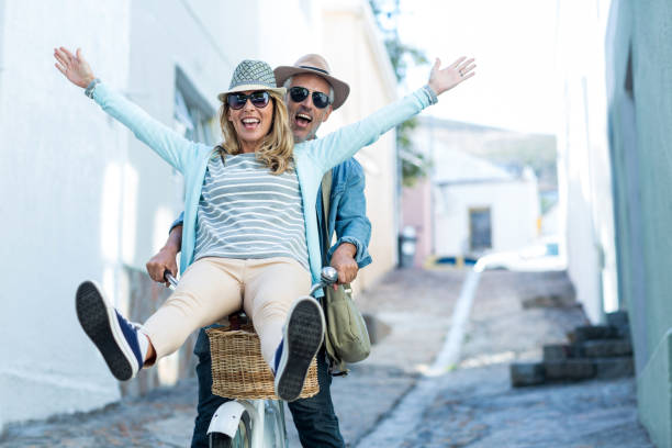Happy couple enjoying while riding bicycle stock photo