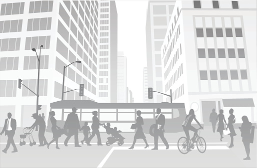 A vector silhouette illustration of a crowded city street with commuters crossing a side walk, a bus traveling through an intersection, and tall office buildings.
