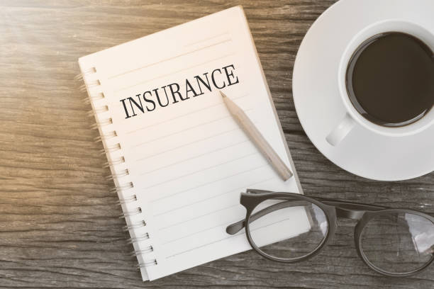 istock Concept insurance message on notebook with glasses, pencil and coffee cup on wooden table. 653284970