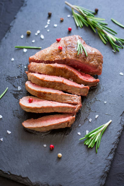 istock Roast beef steak on slate cutting board, top view. Grilled meat 653287784