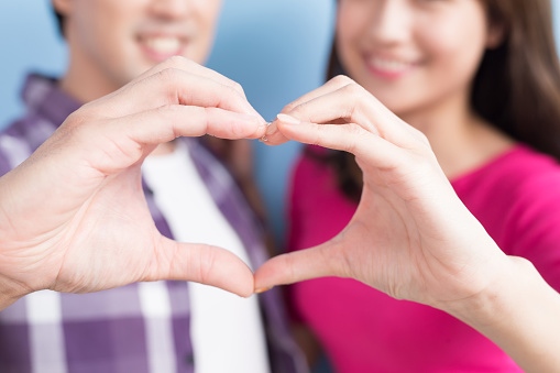 young couple show heart to you isolated on blue background