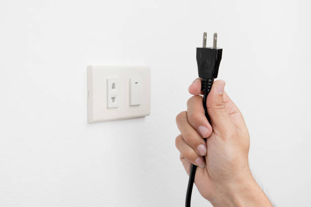 istock Hand of man unplug electric outlet plug on wall white 653306250