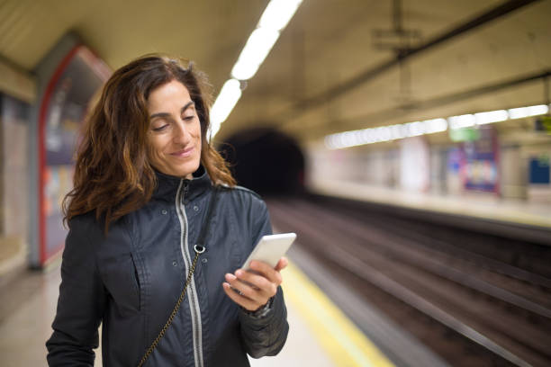 istock smiling woman using phone in subway station 653306722