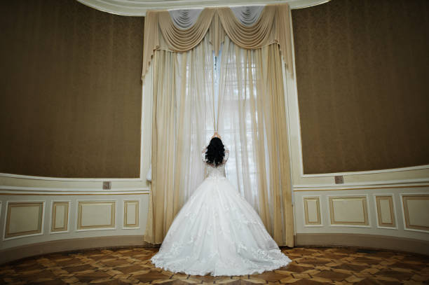 istock Charming brunette bride holding curtains on royal room. 653314844
