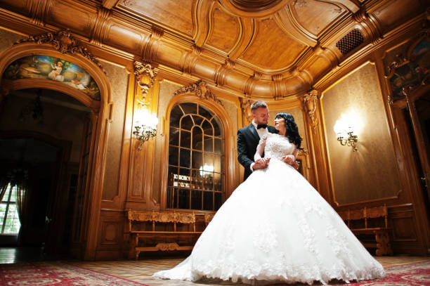 потрясающая свадебная пара в помещении богатая королевская комната с кла�ссическим деревянным дизайном - wedding medieval king bride стоковые фото и изображения