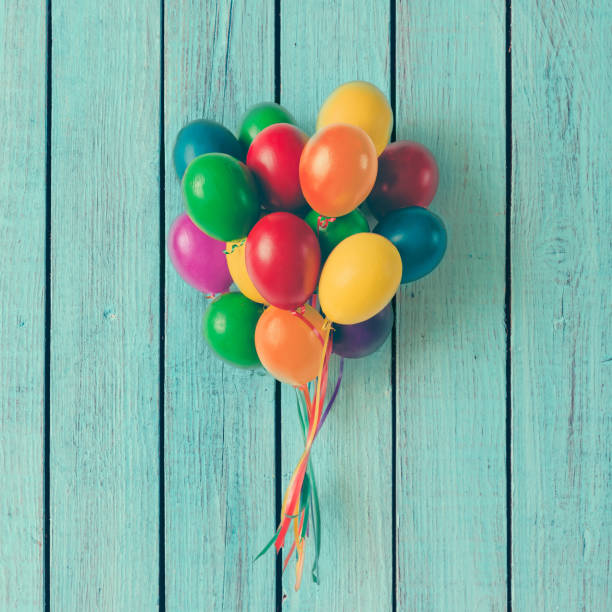 istock Colorful bunch of Easter egg balloons on blue wooden background. Minimal creative concept. Flat lay. 653329810