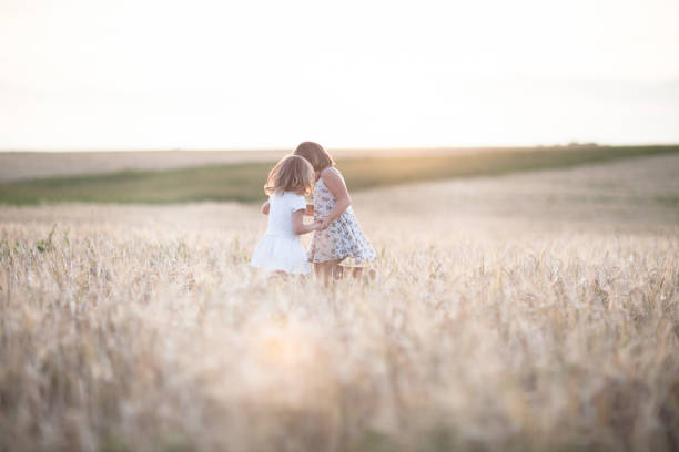 istock Happy emotional sisters dance on the wheat field at sunset 653330882