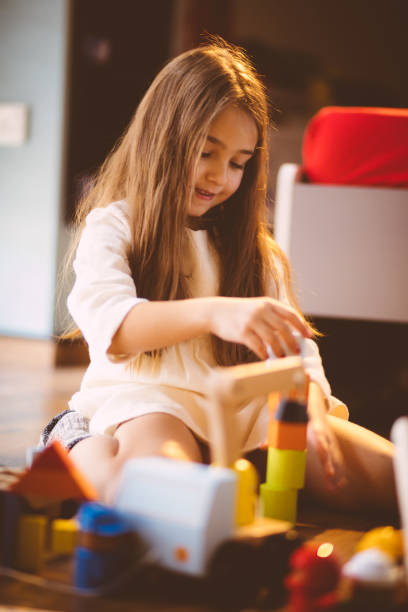 istock Young blond girl playing with toy blocks on the floor 653337288