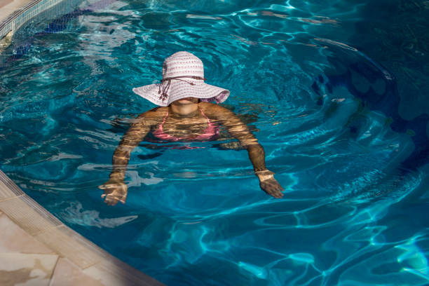 istock Young woman with hat swimming in pool 653340178