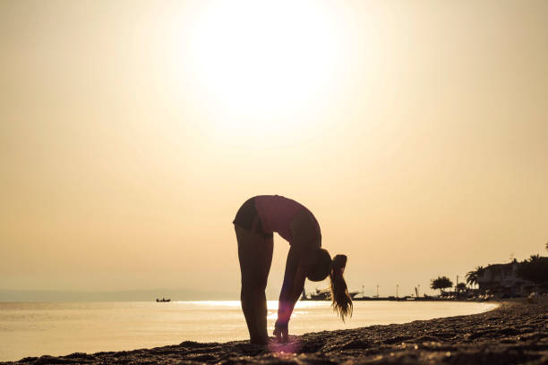 istock Young woman doing gym on sand beach 653343356