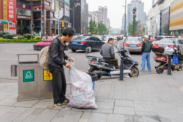 CHENGDU, CHINA - MAY 8, 2016: Chinese homeless looks for food and valuable in a garbage tin on May 8 2016 in Chengdu, China CHENGDU, CHINA - MAY 8, 2016: Chinese homeless looks for food and valuable in a garbage tin on May 8 2016 in Chengdu, China prc stock pictures, royalty-free photos & images