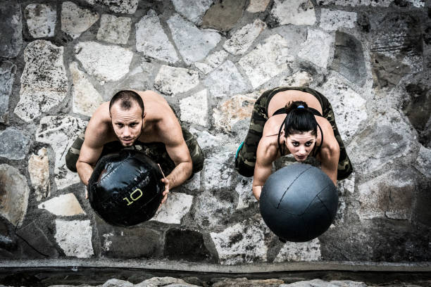 若い男性と女性のクロス トレーニング医学ボールを投げる - crossfit exercising sports training outdoors ストックフォトと画像